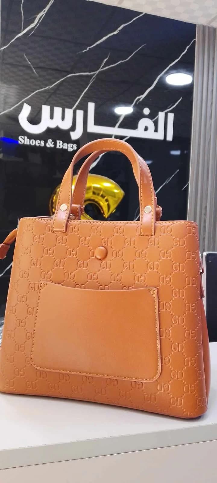 A classic-style handbag with top handles and gold-tone hardware for women.